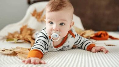 تربیت نوزاد کودکی روی تخت با پستانک در دهان